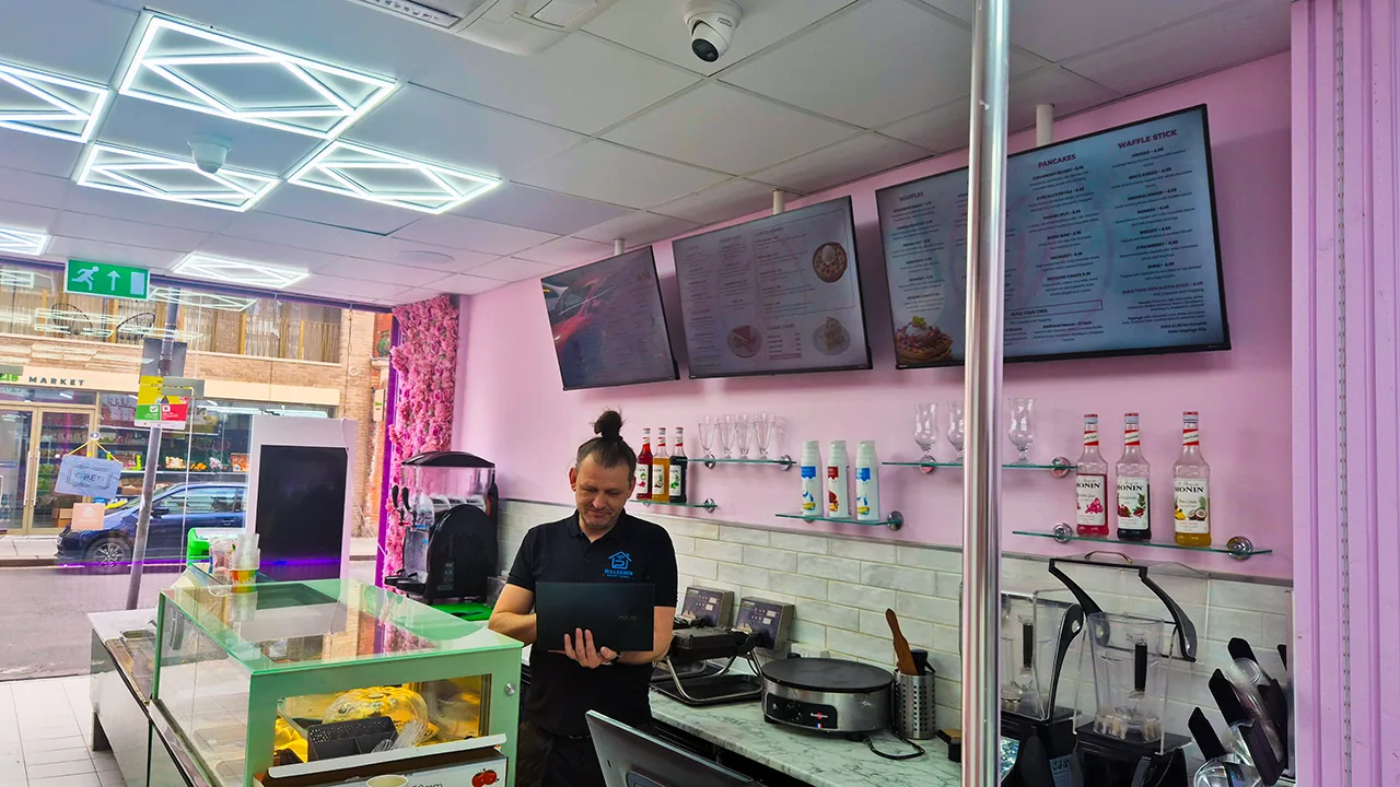 Dome CCTV camera fitted in a cafe ceiling while the setup is checked on a laptop