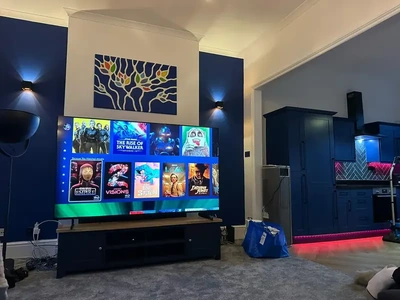 Blue living room with TV media wall lighting and kitchen accent lighting.
