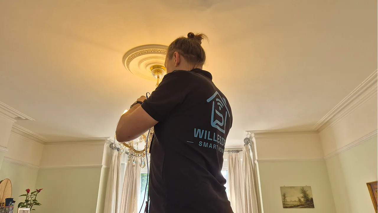 Installer fitting a crystal chandelier in a living room