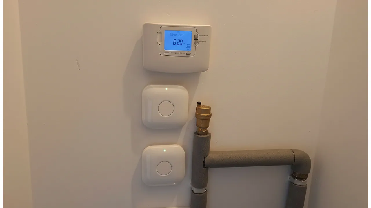 Wall-mounted heating controls beside insulated pipework