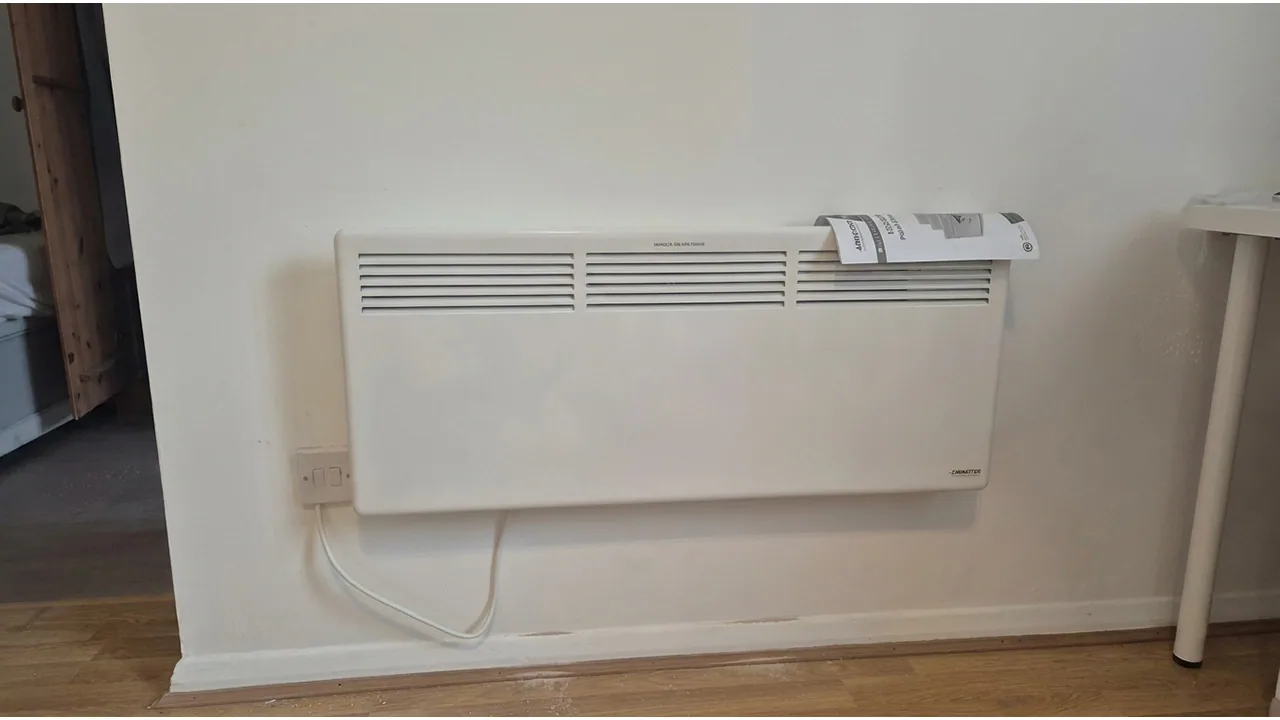 Wall-mounted electric heater installed in a room.