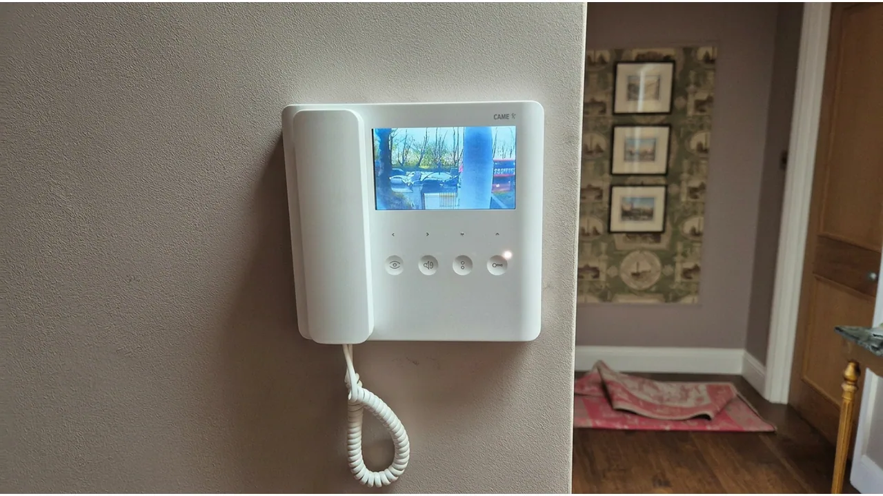 White video intercom monitor and handset showing the entrance camera view.