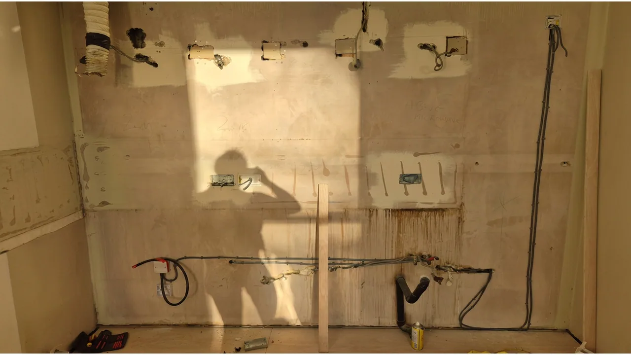 Kitchen wall during first fix with cable routes and accessory positions prepared.