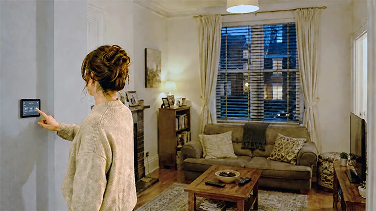 Person using a wall-mounted smart-home control in a living room