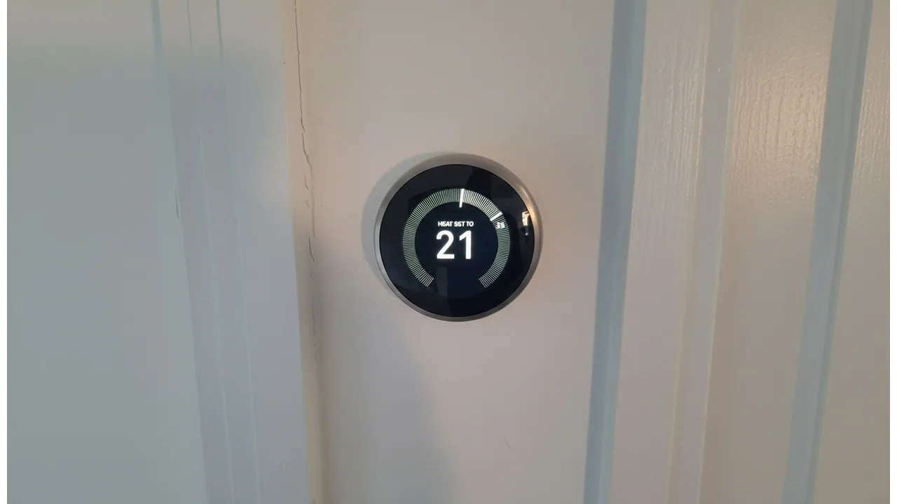 Nest thermostat showing 21 degrees after installation on a hallway wall