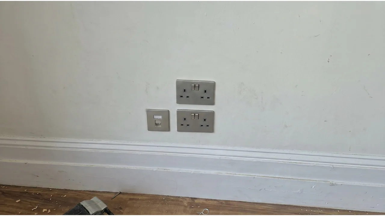 Two metal double sockets and a data plate on a wall.